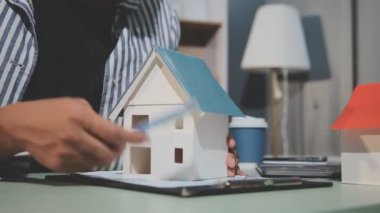İş adamı model ev modelini elinde tutuyor.