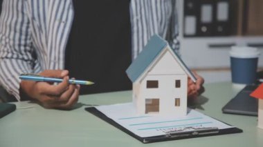 İş adamı ev modeli ve kalemle kağıt tutuyor. Emlakçı ya da ajan konsepti