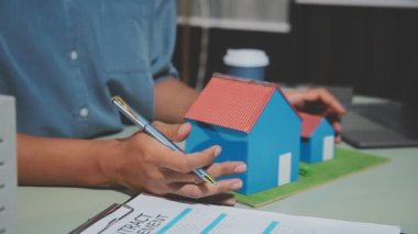 Emlak konsepti. Ev planı olan ev modeli, adam ya da ajan ev modeli ve emlak sigortası planı tutuyor. ev kredisi veya gayrimenkul