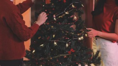 Genç çift Noel ağacı süslüyorlar.