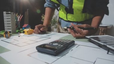 Masada dizüstü bilgisayar, hesap makinesi, plan ve iş yerinin planlarıyla çalışan mühendis. mühendislik ve inşaat tasarımı kavramı.