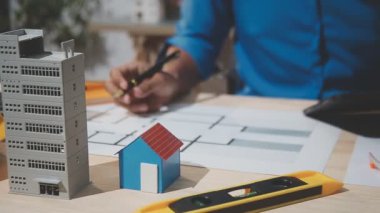 Mühendis ya da mimar mühendisi, planlar, mimari model, inşaat alanı, yapı modeli ve mimari plan, inşaat konseptiyle çalışıyor.