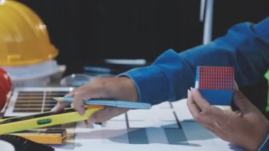 Ofisteki inşaatın planlarını kullanarak kasklı erkek mühendisi kapatın.