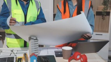 İnşaat alanındaki masanın planlarıyla çalışan mimar mühendisi.