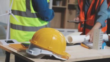 İnşaat mühendisi planlar ve kaskla çalışıyor.