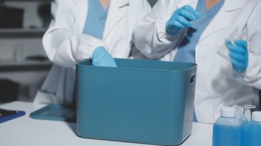 Koruyucu kıyafetli bilim adamı laboratuarda matarayı tutuyor.