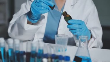 Koruyucu gözlüklü bilim adamı deney tüpü ve kimyasal sıvı tutuyor..