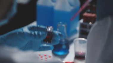 Kapat. Bilim adamı elinde sıvı bir test tüpü tutuyor..