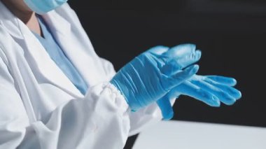 Kadın doktor mavi eldiven tutuyor.