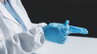 Beyaz lateks eldivenli doktor elinde beyaz hap tutuyor.