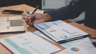 Ofisteki ahşap masada dizüstü bilgisayar ve akıllı telefonla çalışan iş adamı. Mali tabloyla, iş konseptiyle.