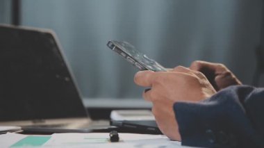 İşadamı ofiste dizüstü bilgisayar ve akıllı telefonla çalışıyor.