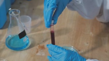 Laboratuvarda test tüpü olan eldivenli bilim adamı.