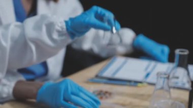 Laboratuvarda test tüpleriyle deney yapan genç bilim adamının ellerini kapatın.