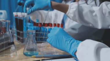 Laboratuvarda deney tüpünü sıvı ve pipetle tutan bilim adamının yakınına..