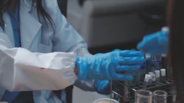 Kadın laboratuvar asistanı elinde kan tüpü tutuyor..