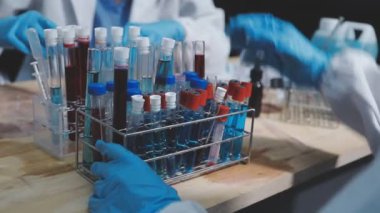 Laboratuvarda üzerinde kan örneği olan test tüpü tutan koruyucu eldivenli bilim adamlarının yakınına..