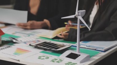 Rüzgâr türbini ve dizüstü bilgisayarı olan iş kadınları ofiste.