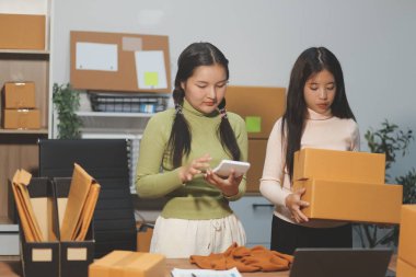 Girişim KOBİ küçük işletme girişimcisi önlük giyen Asyalı kadın dizüstü bilgisayar ve kutu kullanarak çevrimiçi müşterilere, çevrimiçi sme iş fikirlerine satış hazırlamak için siparişleri alır ve gözden geçirir.