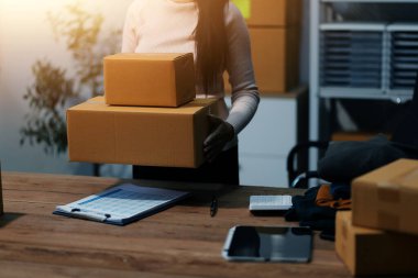 Girişim KOBİ küçük işletme girişimcisi önlük giyen Asyalı kadın dizüstü bilgisayar ve kutu kullanarak çevrimiçi müşterilere, çevrimiçi sme iş fikirlerine satış hazırlamak için siparişleri alır ve gözden geçirir.