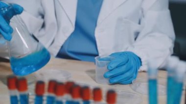 Laboratuvarda çalışan bilim adamı kimyasal örneklerle dolu tüpleri tutuyor.