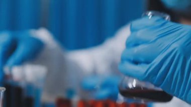 Test tüpüyle koruyucu maskeli laboratuvar çalışanlarını kapatın..