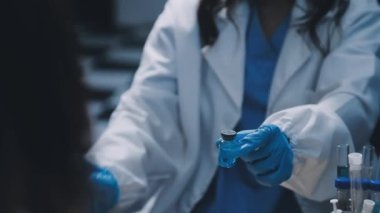 Tıbbi eldivenli kadın doktor ve elinde şırınga tutan koruyucu eldivenler.