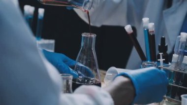Yakın plan - koruyucu eldivenli erkek bilim adamının laboratuarda deney yapması.