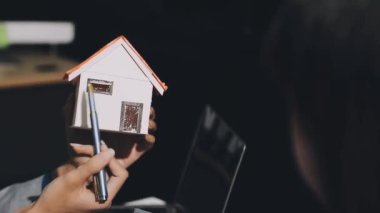 Emlakçı ev modelini elinde tutuyor.