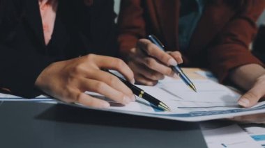 İş adamları iş yerlerinde mali tabloları tartışıyor ve kağıda yazı yazıyorlar.