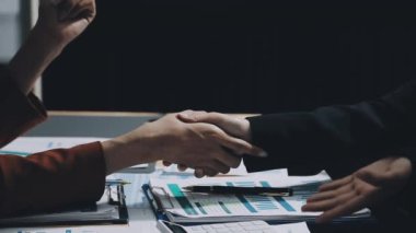 Modern çatı katında iki işadamı el sıkışıyor.