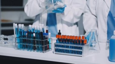 Mavi üniformalı laboratuvar çalışanı mikroskopla çalışıyor.