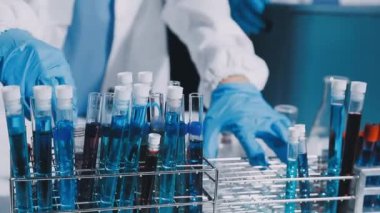 Laboratuvar asistanı elinde bardak, elinde de sıvı var. kimyasal deney