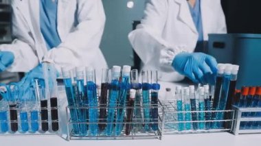 Laboratuvarda tüpleri tutan bilim adamlarının elleri yakın plan.