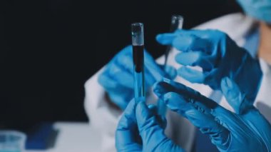 Laboratuvarda sıvı içeren bir test tüpü tutan bilim adamı.