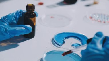 Laboratuvarda mavi tüplü bir örnek tutan bilim adamı.