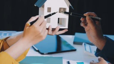 Bir erkek ve bir kadın el ele tutuştukları kalem bir ev modeli..