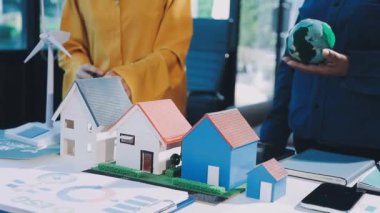 İş dünyası, insanlar ve teknoloji, iş adamlarının ellerinde model ev modeli ve model arka planda.