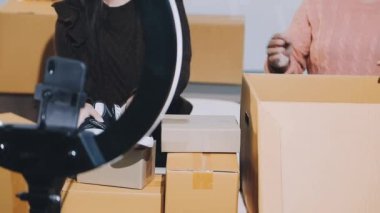 Genç Asyalı bir adam bir karton kutuda online mağaza için kutu topluyor. çevrimiçi dağıtım hizmeti kavramı