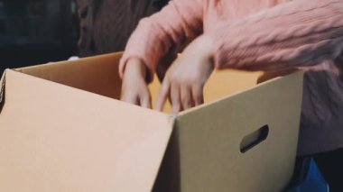 Karton kutu tutan genç bir kadın.