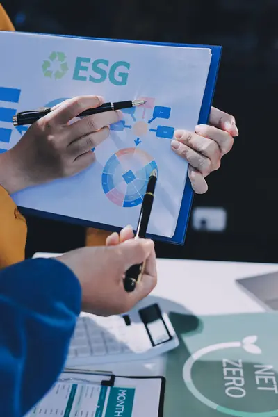 ESG 'nin çevresel sosyal yönetimi, çevre dostu şirket toplantılarında, temiz ve sürdürülebilir gelecekteki ekoloji için çevre korumasını uygulayan iş adamlarıyla dizüstü bilgisayarda sergileniyor. Önde.