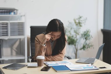 Yorgun ve Asyalı bir kadının portresi ofiste vergi bilgisayarıyla çalışıyor. Üzgün, mutsuz, endişeli, depresyon ya da çalışan hayatı stres konsepti