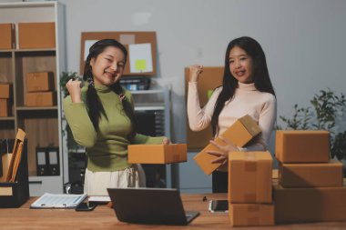 Girişim KOBİ küçük işletme girişimcisi önlük giyen Asyalı kadın dizüstü bilgisayar ve kutu kullanarak çevrimiçi müşterilere, çevrimiçi sme iş fikirlerine satış hazırlamak için siparişleri alır ve gözden geçirir.