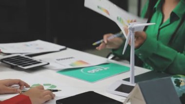 Genç Asyalı iş adamları ofiste yeni bir iş planı üzerinde çalışıyorlar. Laptop kullanıyorlar, yeşil bitkilerle tablet kullanıyorlar.