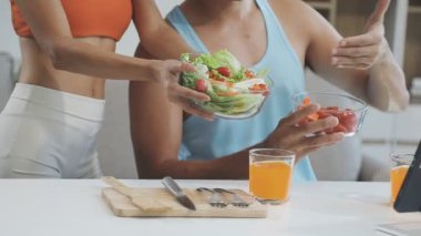 Genç adam yemek yerken dizüstü bilgisayar tutuyor.