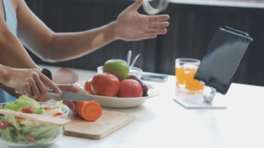 Genç bir kadın mutfakta yemek pişiriyor..