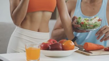 Çift mutfakta eğleniyor ve taze sebze yiyor.