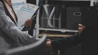 İş adamı ve iş kadını modern ofiste belgelerle el sıkışıyor