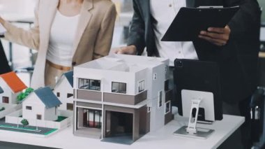 Emlakçı emlak konseptinin arka planında ev modeli ve anahtar olan ev modelini tutuyor.