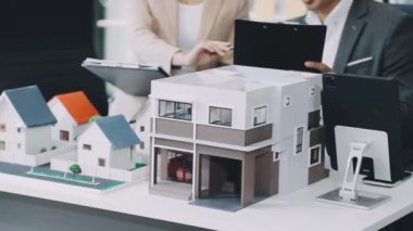 Emlakçı bir modelle model ev modelini tartışıyor.